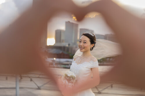 ハートの手の向こうに新婦とみなとみらいの背景