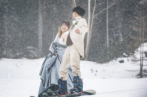ロミオとジュリエットのように手を繋いでスノーボードで滑るフォトウェディング