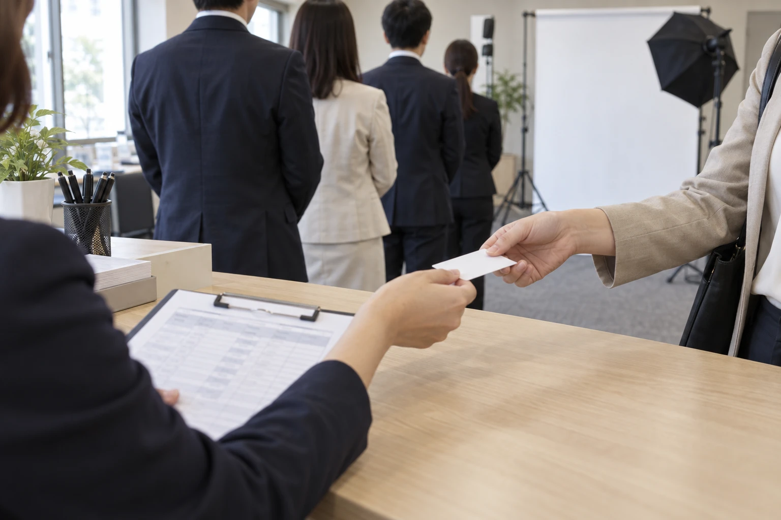 社員撮影の受付で名札を受け取り撮影を待つ社員の列のイメージ