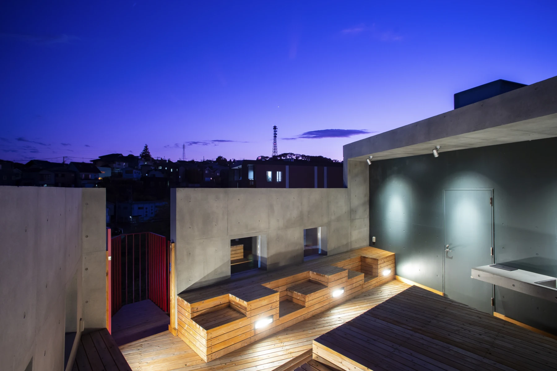 夕暮れの空の下で照明が灯る住宅の屋上テラス