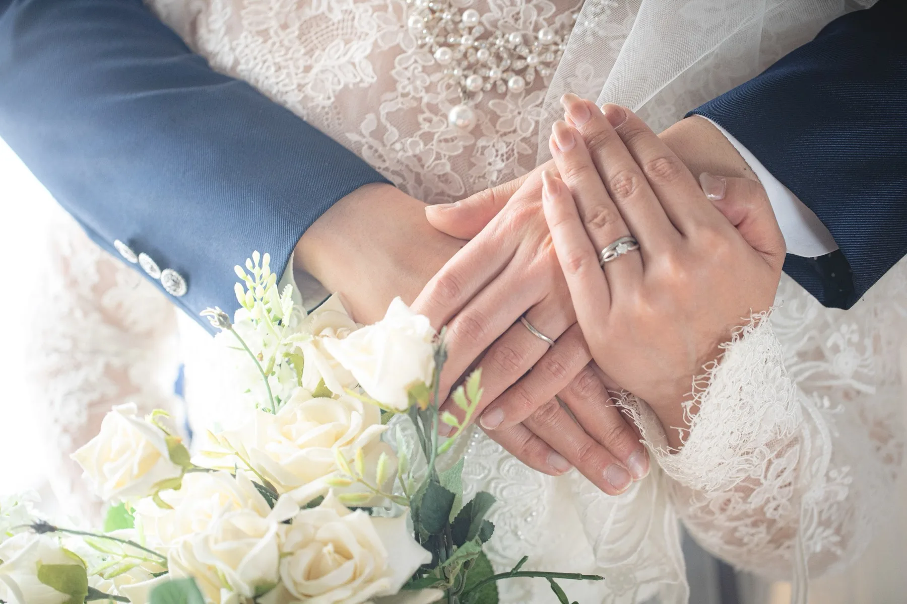 重ねた手元の結婚指輪とホワイトローズのブーケ、フォトジェリッシュ横浜店のスタジオ撮影