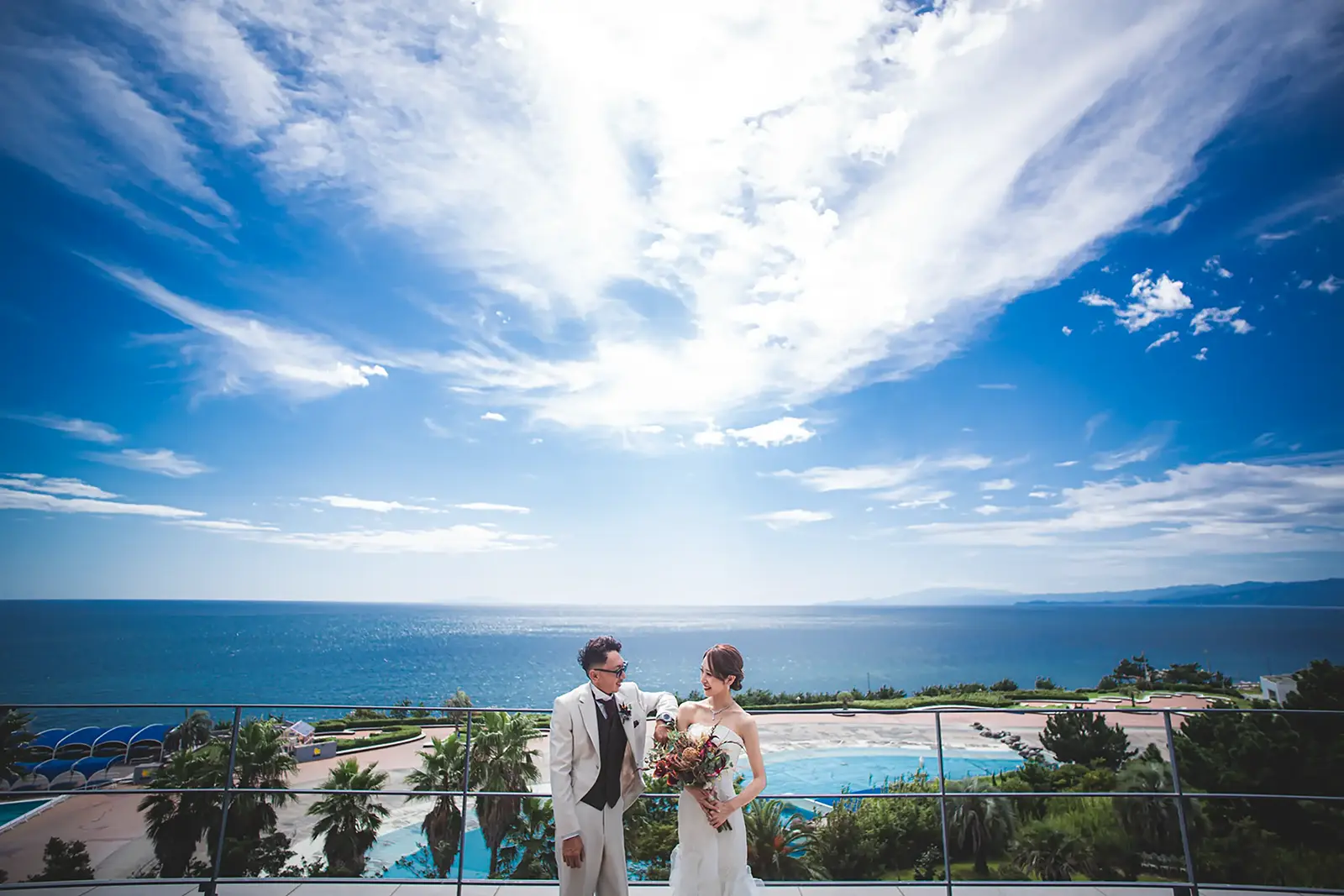 湘南の海を一望できる絶景ロケーションで向かい合う新郎新婦のフォトウェディング写真