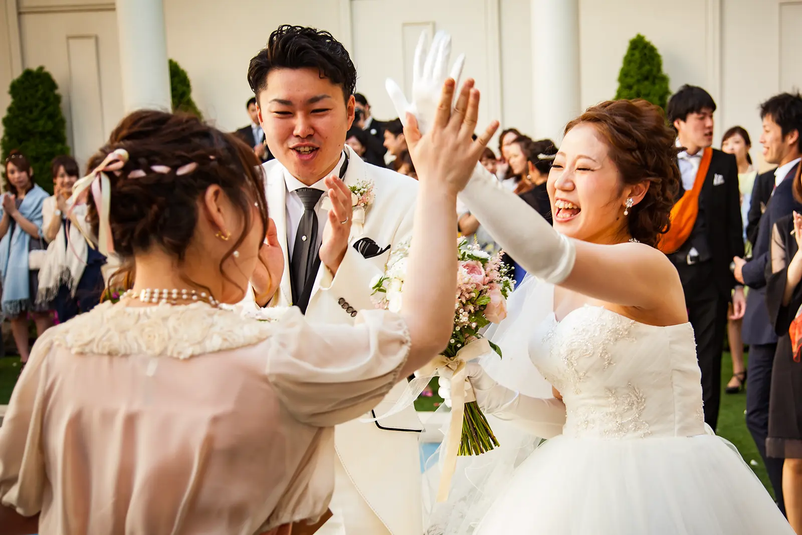 披露宴後にゲストとハイタッチを交わす新郎新婦のウェディング写真