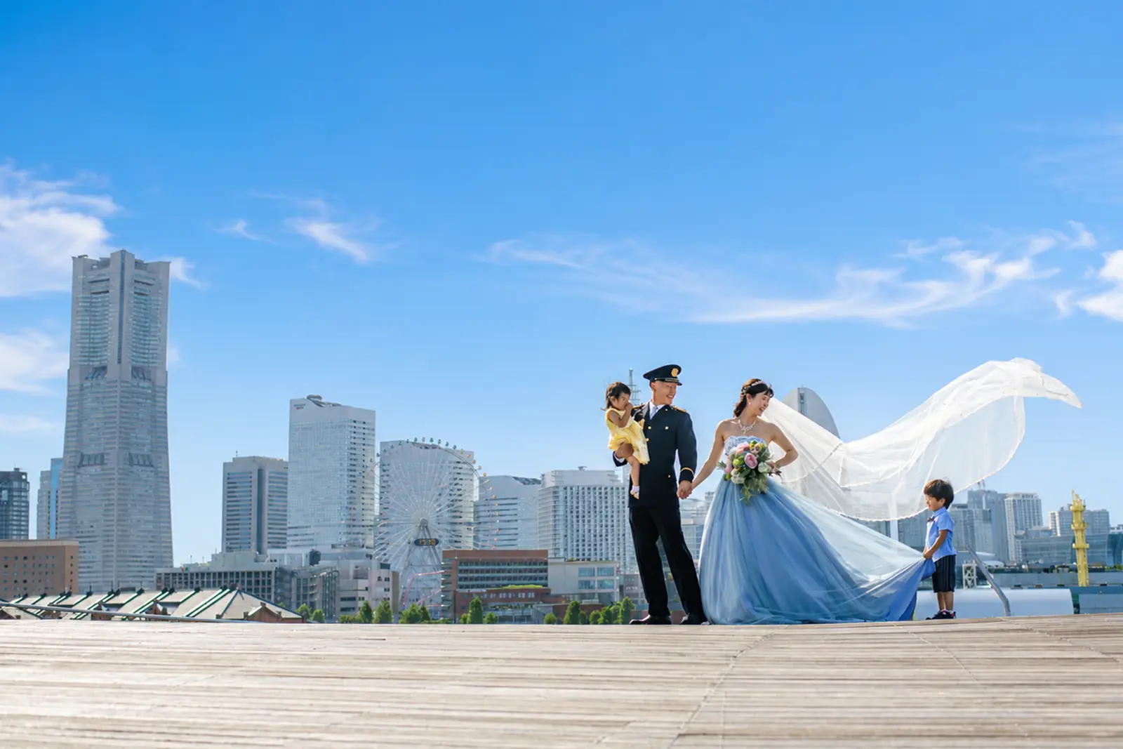 みなとみらいの景色を背景に家族と一緒に並ぶ新郎新婦のフォトウェディング写真