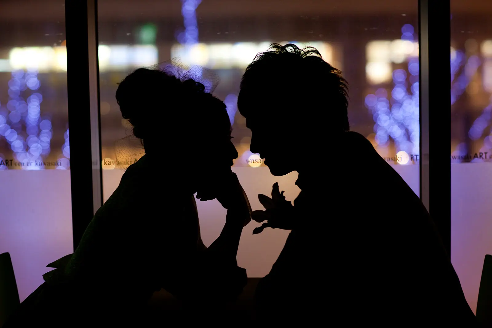 横浜の夜景を背景に向かい合う新郎新婦のシルエット写真