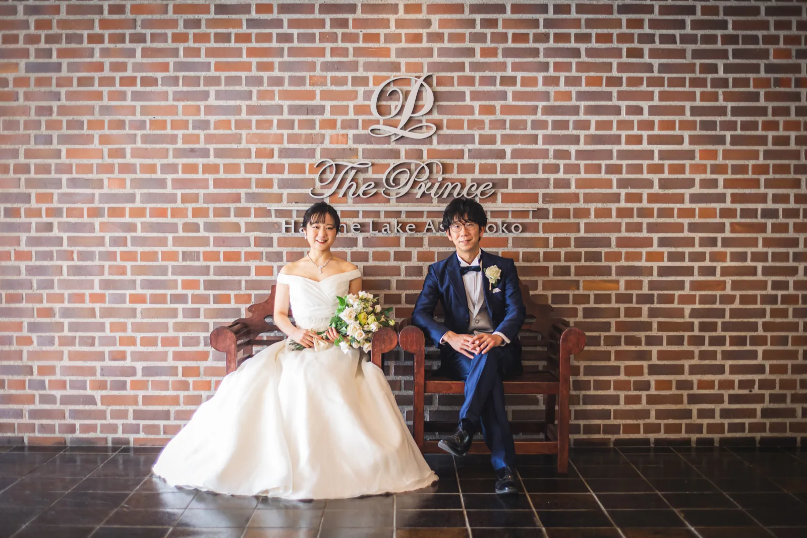 ザ・プリンス箱根芦ノ湖のロゴ前でホテルのポスターのように撮る新郎新婦