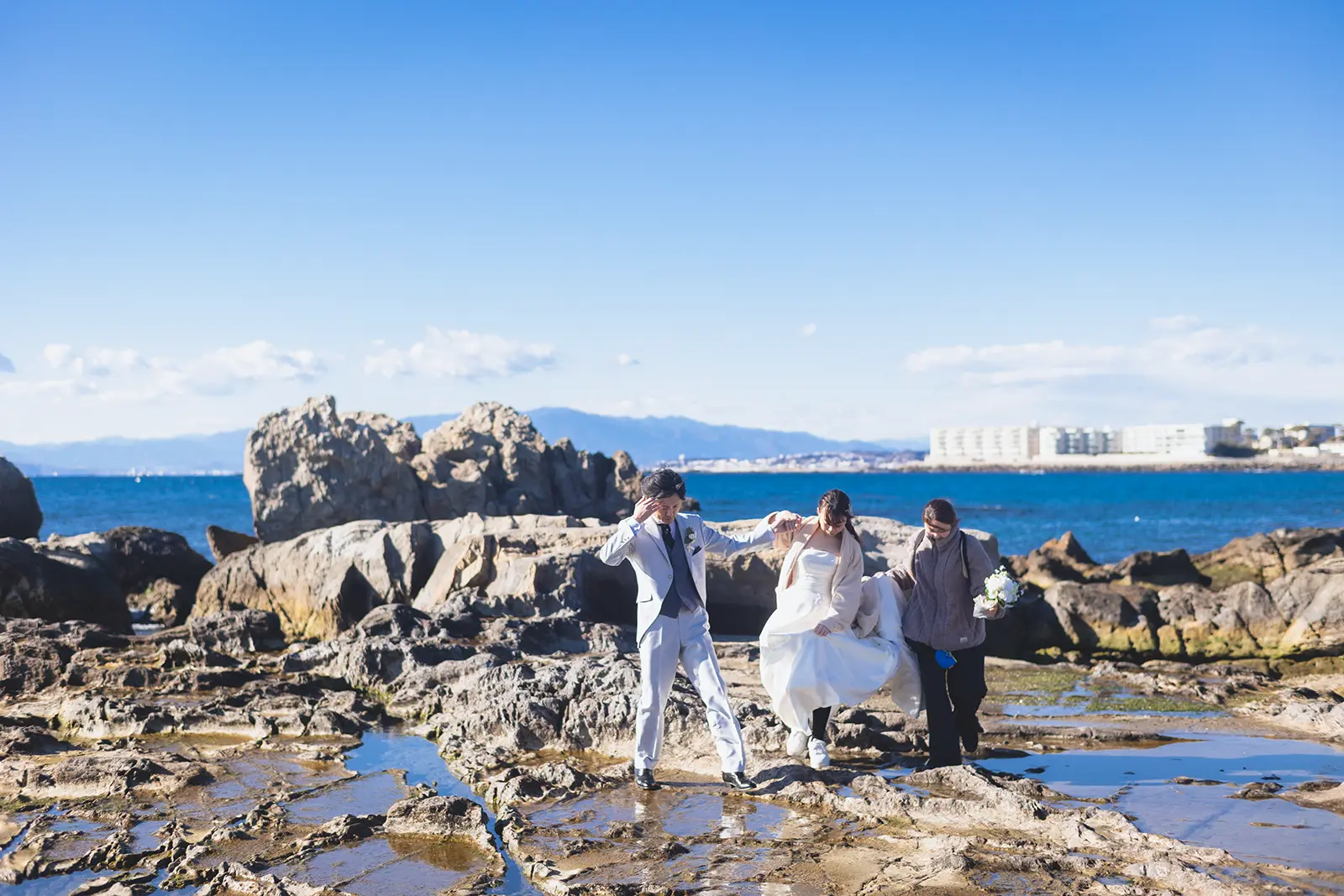 小磯の鼻の岩場でスタッフがサポートしながら移動する新郎新婦