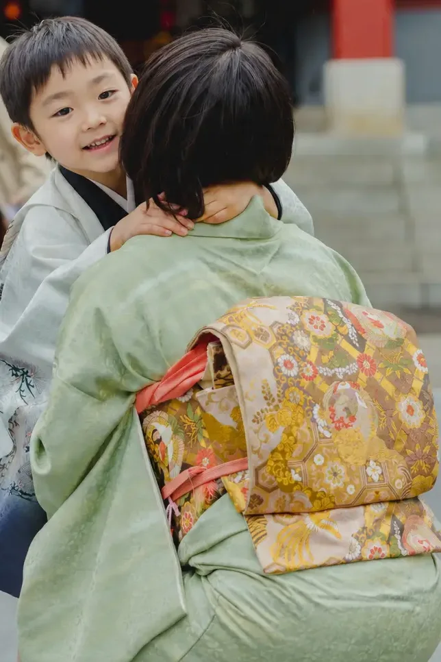 訪問着の母に抱きつきながら肩ごしに振り返る5歳の男の子、日枝神社での七五三出張撮影（東京）
