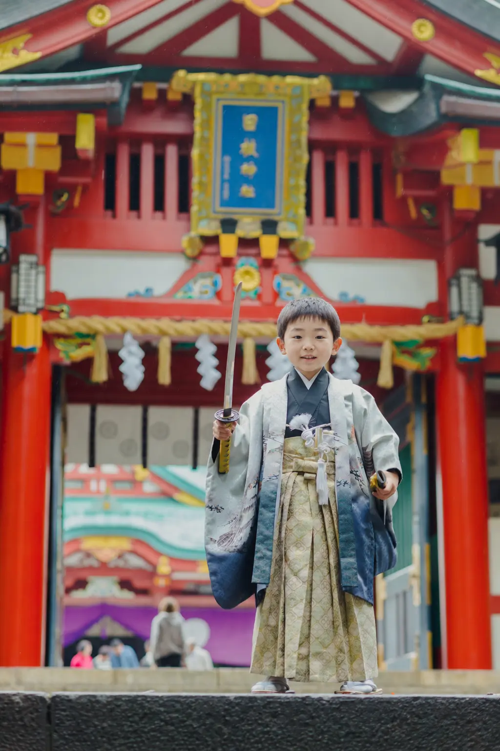 日枝神社の社殿前で刀のような小道具を高く掲げる羽織袴姿の5歳の男の子、七五三出張撮影（東京）