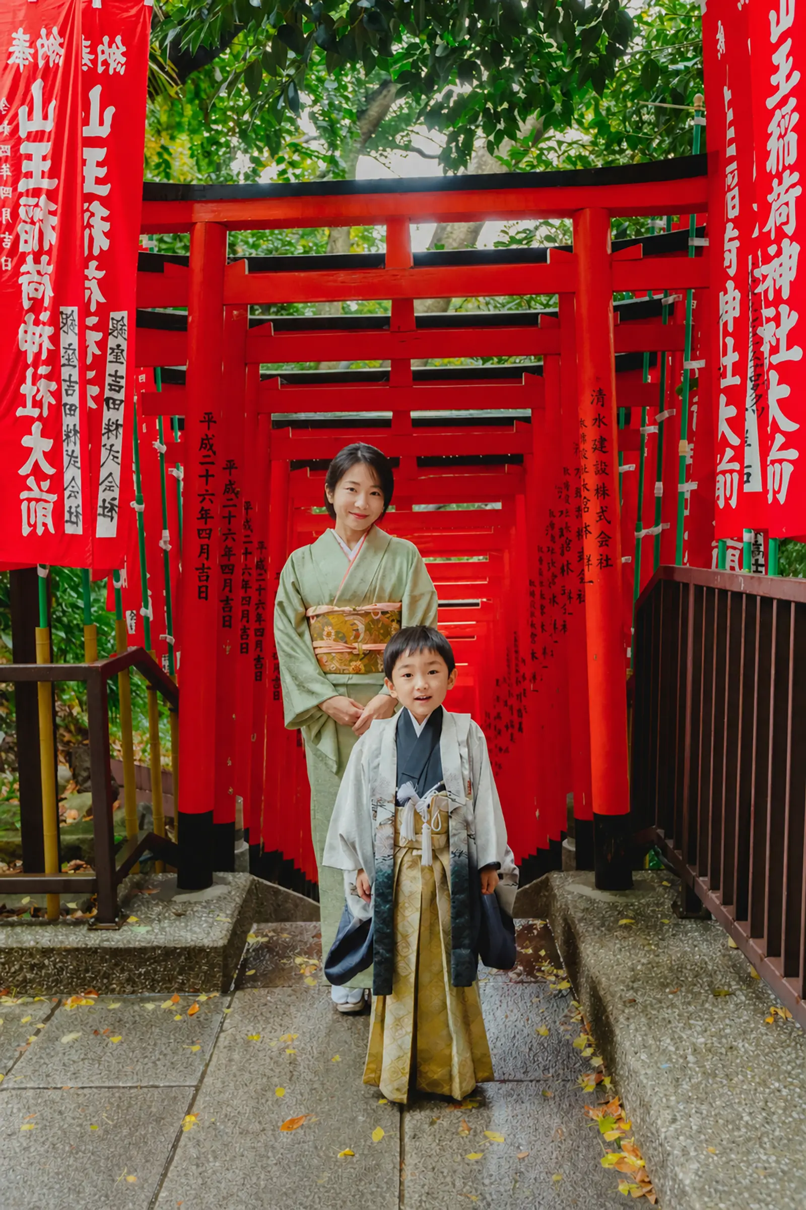 山王稲荷神社の朱い幟と千本鳥居を背に立つ5歳の男の子と母、日枝神社での七五三出張撮影（東京）