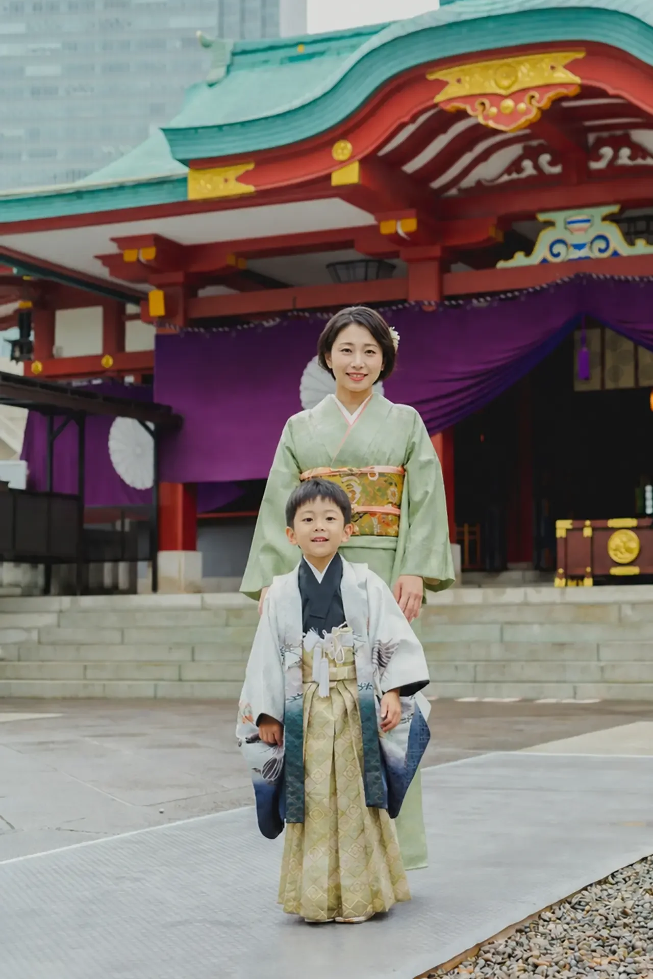 日枝神社の社殿と背後の高層ビルを背に並んで立つ5歳の男の子と母、七五三出張撮影（東京・永田町）