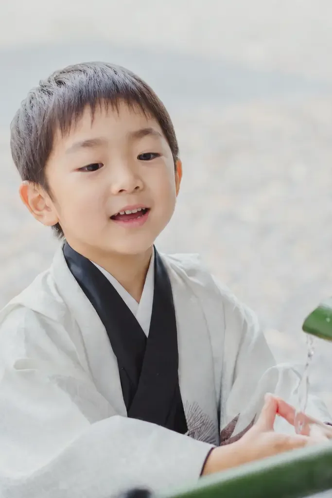 日枝神社の手水舎で竹の樋から落ちる水に手を伸ばす5歳の男の子、七五三出張撮影（東京・永田町）
