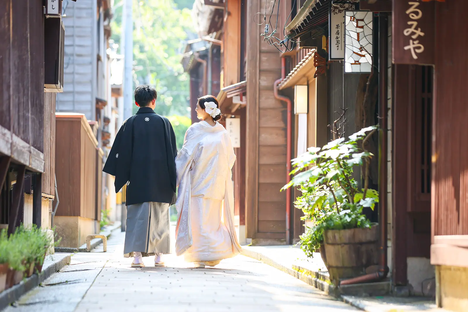 金沢のひがし茶屋街の小道を歩く白無垢姿の新婦と紋付袴の新郎の後ろ姿