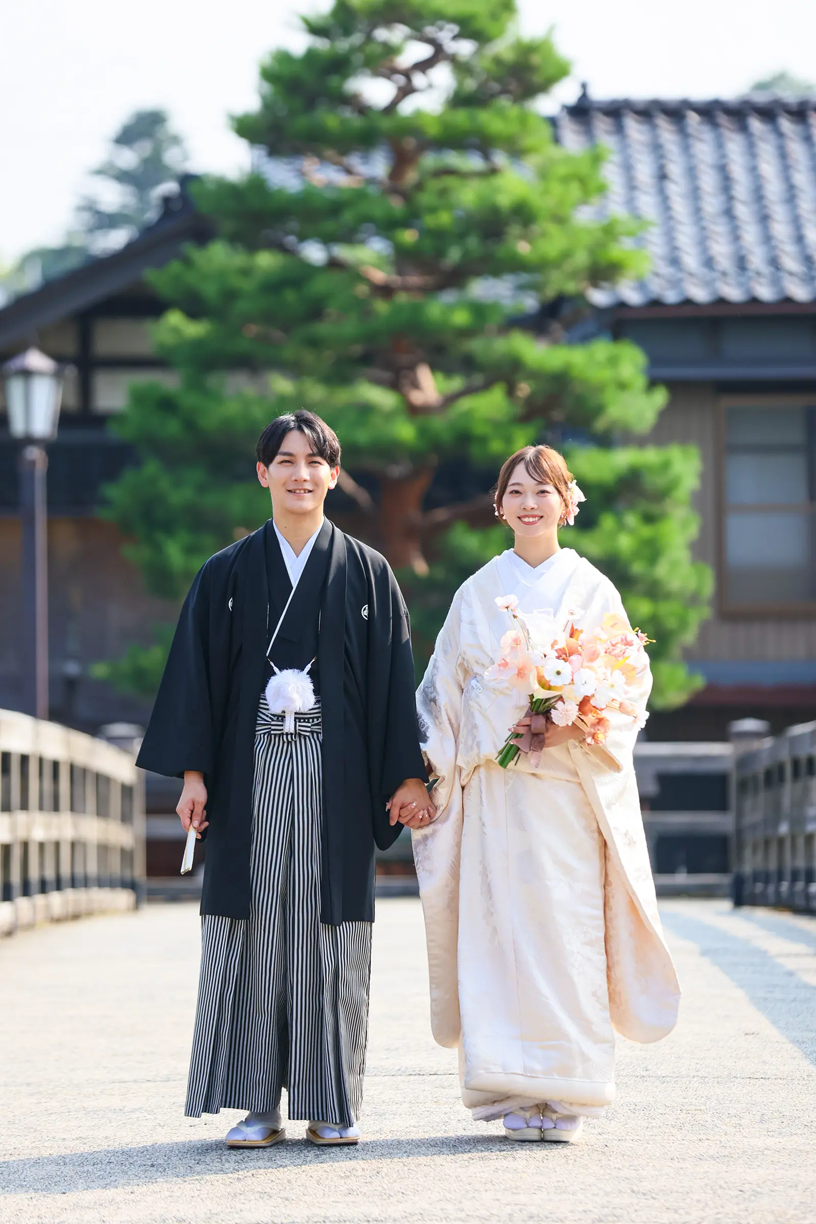 金沢で緑を背景に向かい合う白無垢姿の新婦と紋付袴の新郎