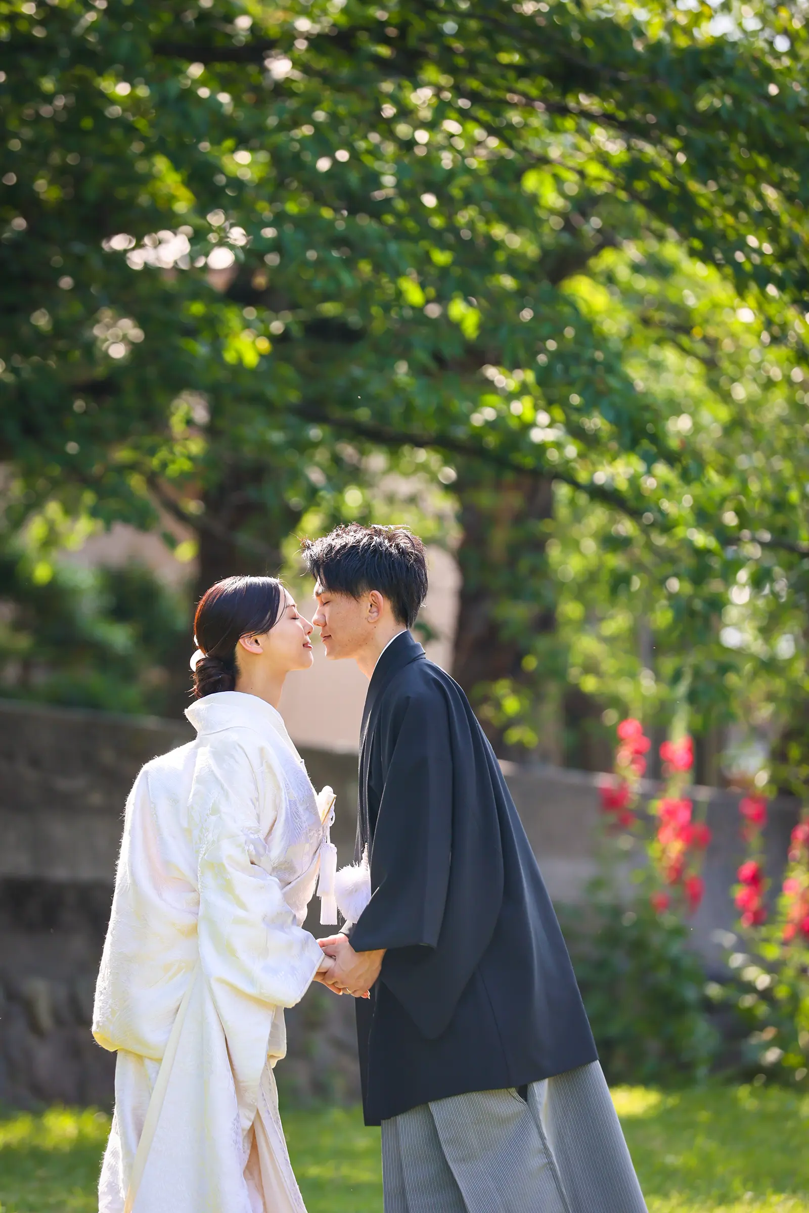 金沢で緑を背景に向かい合う白無垢姿の新婦と紋付袴の新郎