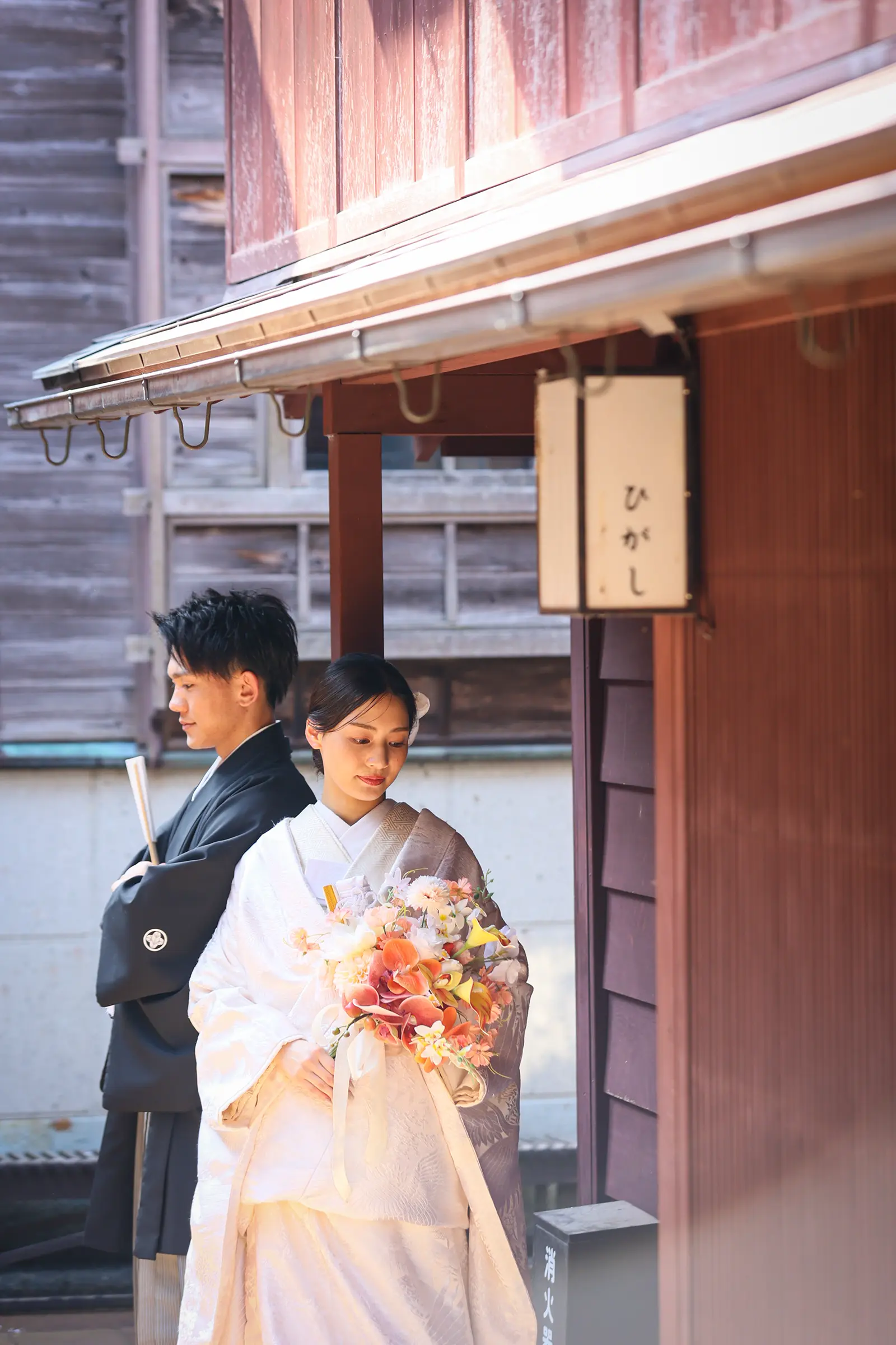 金沢のひがし茶屋街の町家前で白無垢姿の新婦と紋付袴の新郎が並ぶ様子