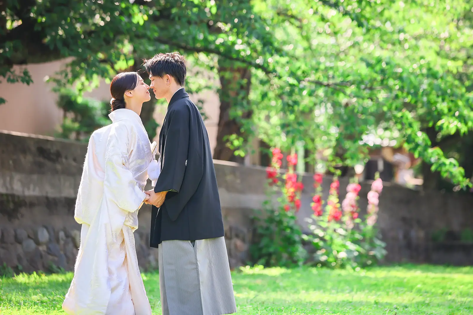 金沢のひがし茶屋街で夏の緑の中、新緑を背景に向かい合う白無垢姿の新婦と紋付袴の新郎