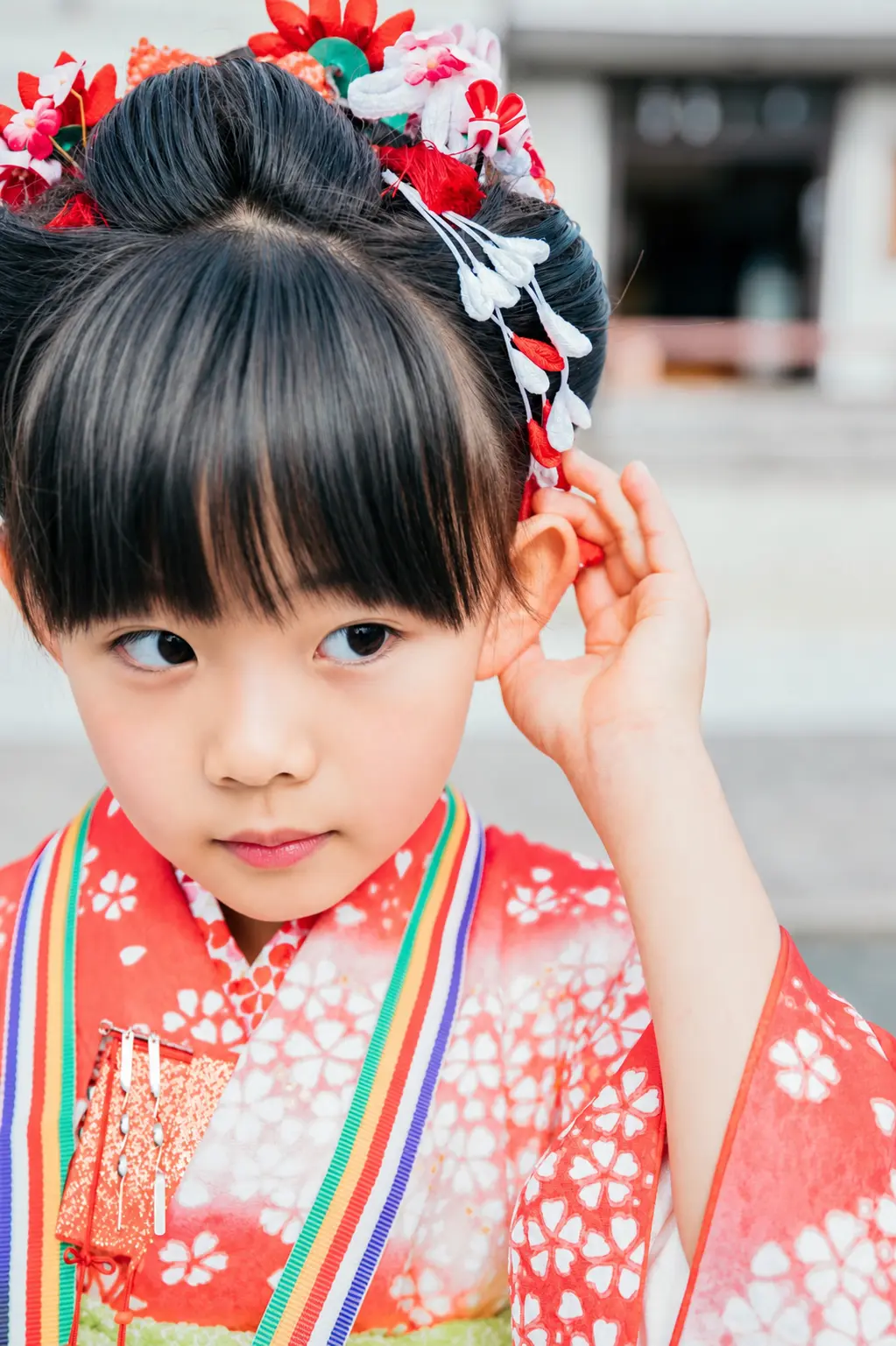 日本髪のびらびら簪に手をやる7歳の女の子、虹色の重ね衿と朱赤の四つ身の七五三（本牧神社・横浜）