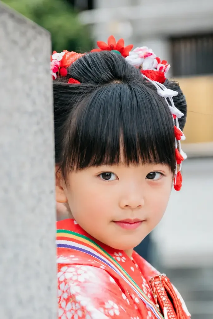 本牧神社の石柱のかげから顔をのぞかせて笑う7歳の女の子、四つ身の七五三（横浜市中区）