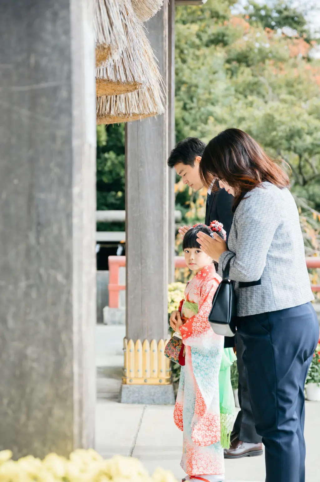 本牧神社の拝殿前、大注連縄の下でご家族と並んで参拝する7歳の女の子の七五三（横浜市中区）
