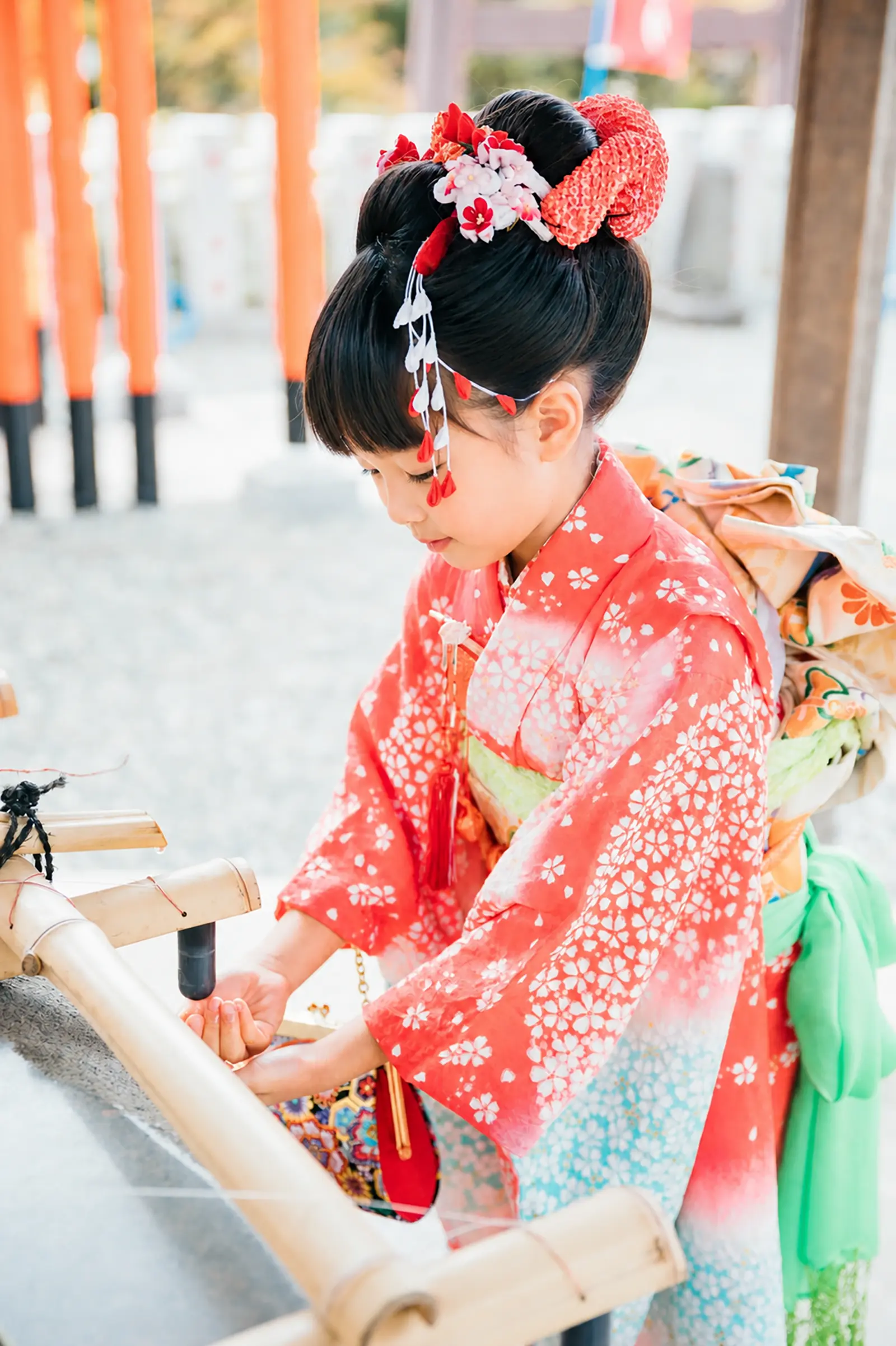 本牧神社の手水舎で竹樋から落ちる水に手を差し出す7歳の女の子、四つ身の七五三（横浜）