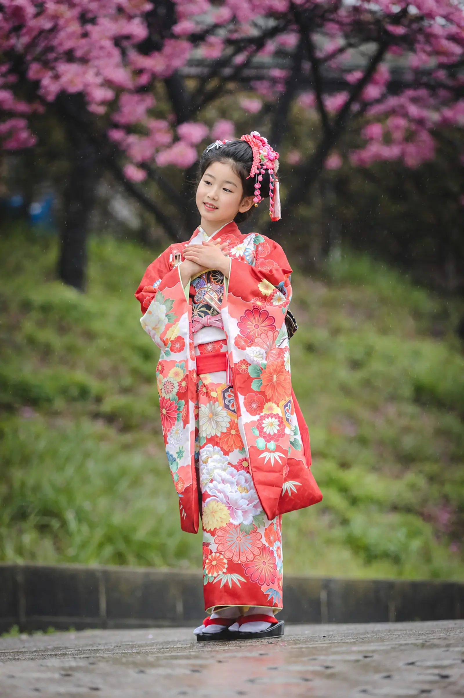 桜を背に雨粒の中で微笑む7歳の女の子、四つ身姿の七五三出張撮影（本牧神社・横浜）