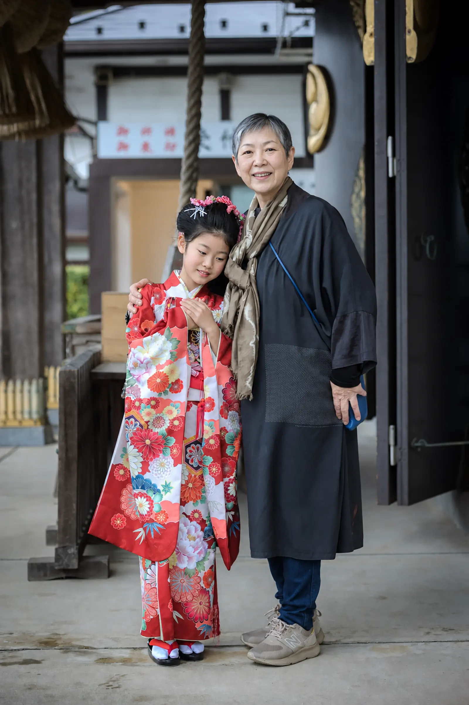 年上のご家族に肩を抱かれる7歳の女の子、四つ身姿の七五三（本牧神社・横浜）