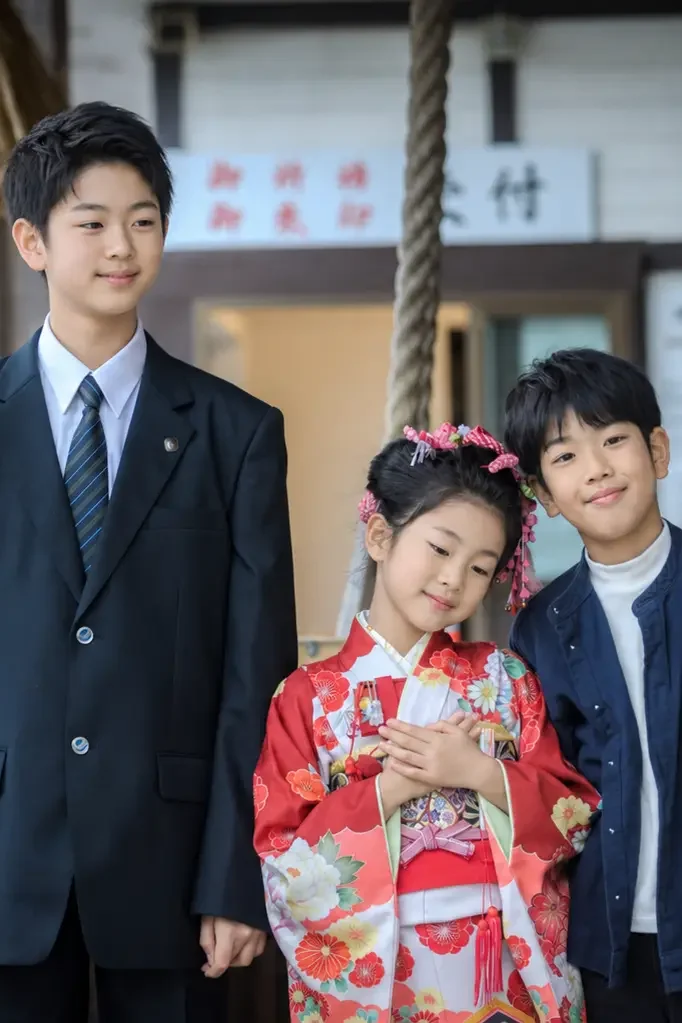 きょうだい3人で寄り添う七五三の記念写真、四つ身の7歳の女の子と学生服の兄（本牧神社・横浜）