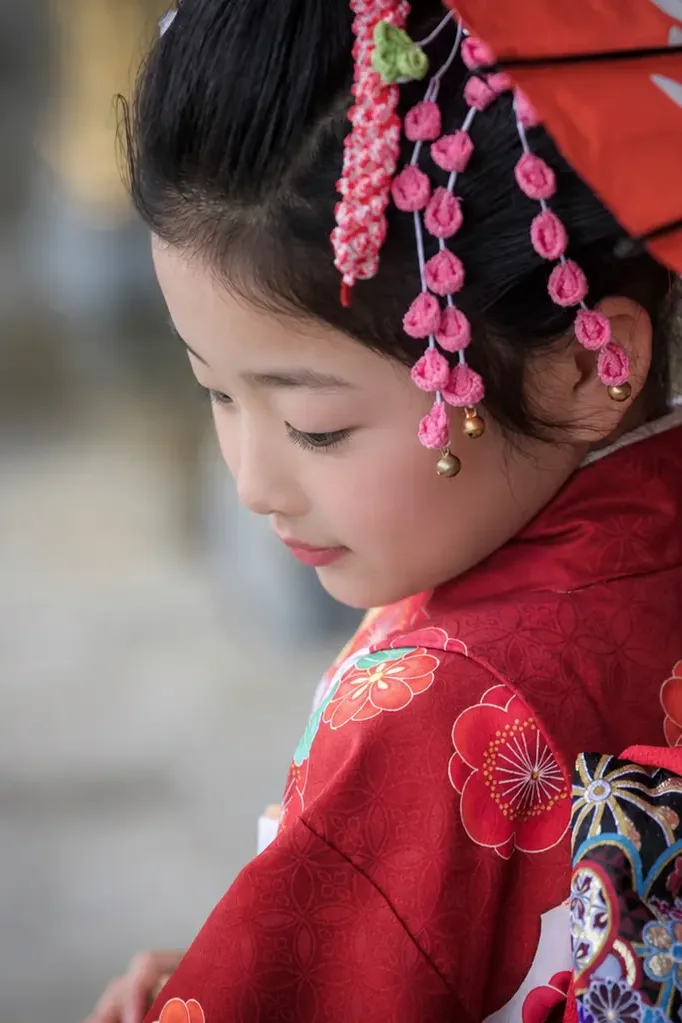 和傘を持ち足元を見つめる7歳の女の子の横顔、四つ身姿の七五三（本牧神社・横浜）