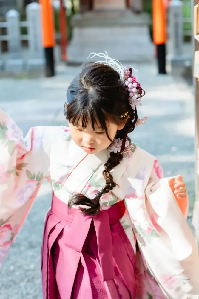 絵馬掛けに並ぶ絵馬へそっと手を伸ばす、袴すがたの7歳の女の子。星川杉山神社の七五三出張撮影（横浜市保土ケ谷区）