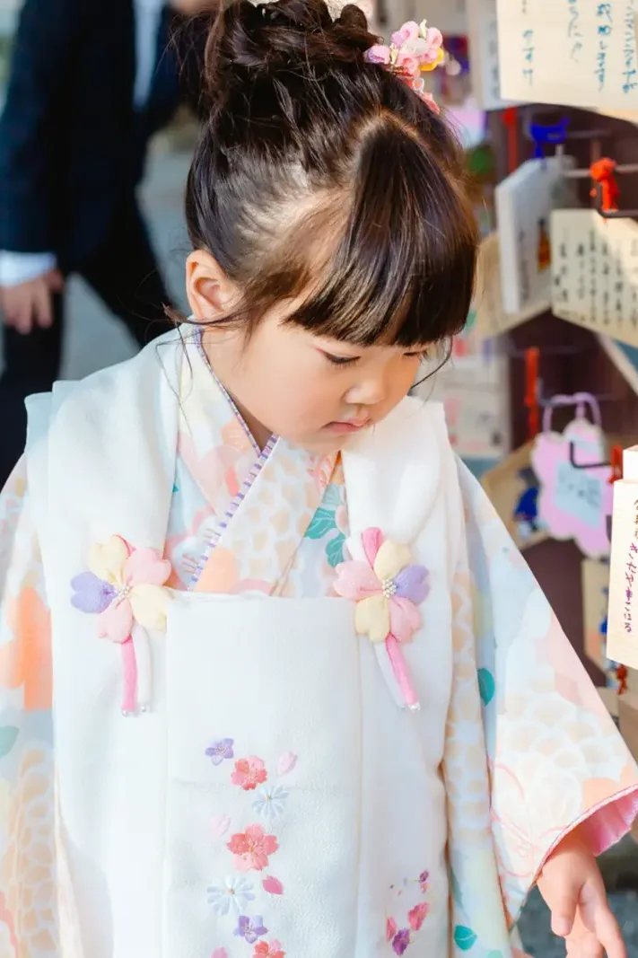 絵馬掛けの前で絵馬をじっと見下ろす3歳の女の子、七五三の被布姿（伊勢山皇大神宮・横浜）