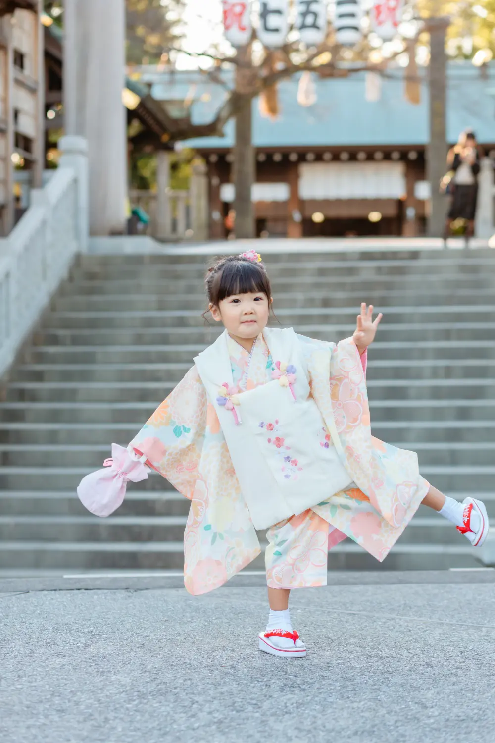 石段の前で片足を上げてポーズをとる3歳の女の子、七五三の被布姿（伊勢山皇大神宮・横浜）