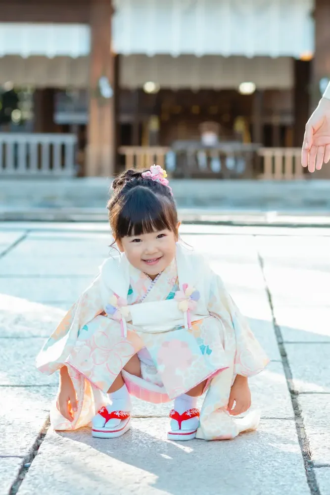 拝殿前の石畳にしゃがんで笑う3歳の女の子、七五三の着物姿（伊勢山皇大神宮・横浜）