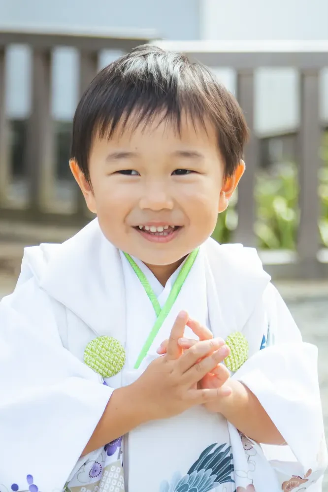 小さな手を合わせてはにかむ3歳の男の子、白い被布姿の七五三（伊勢山皇大神宮・横浜）