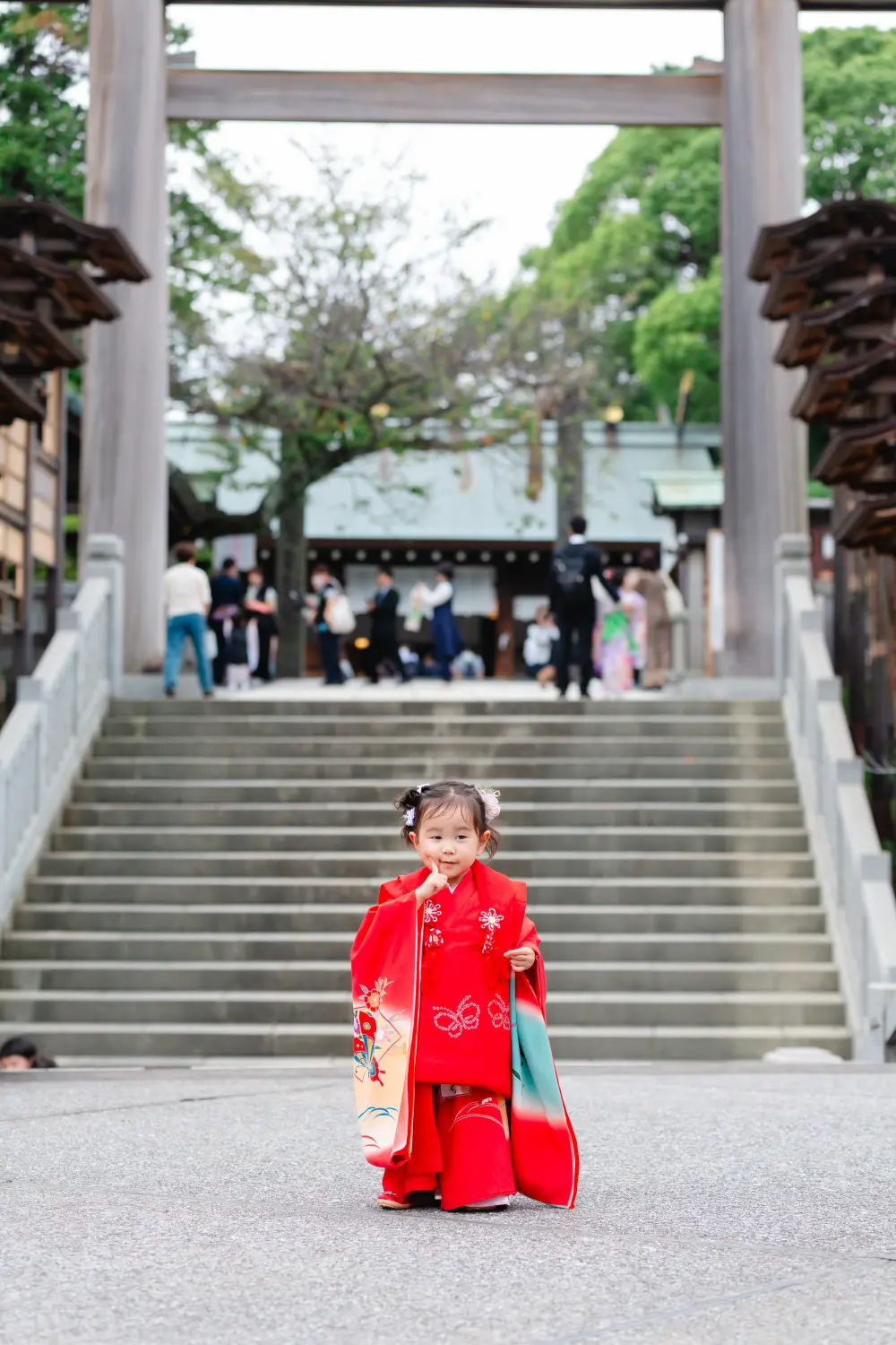 大鳥居と石段の中央に小さく立つ朱赤の被布姿の3歳の女の子、七五三出張撮影（伊勢山皇大神宮・横浜）