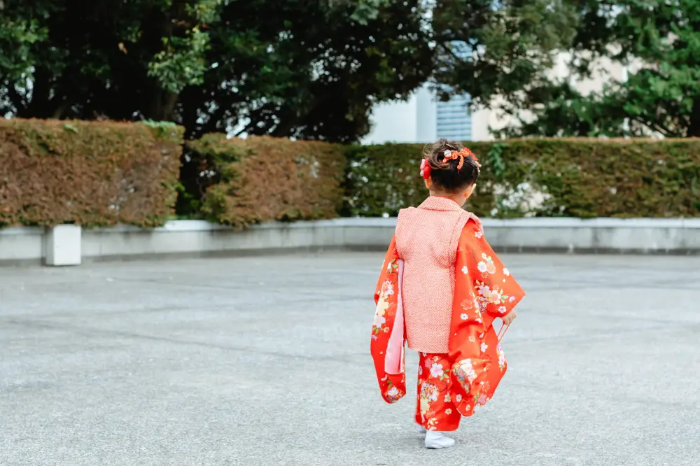 境内を駆けていく赤い被布姿の3歳の女の子の後ろ姿、七五三（伊勢山皇大神宮・横浜）