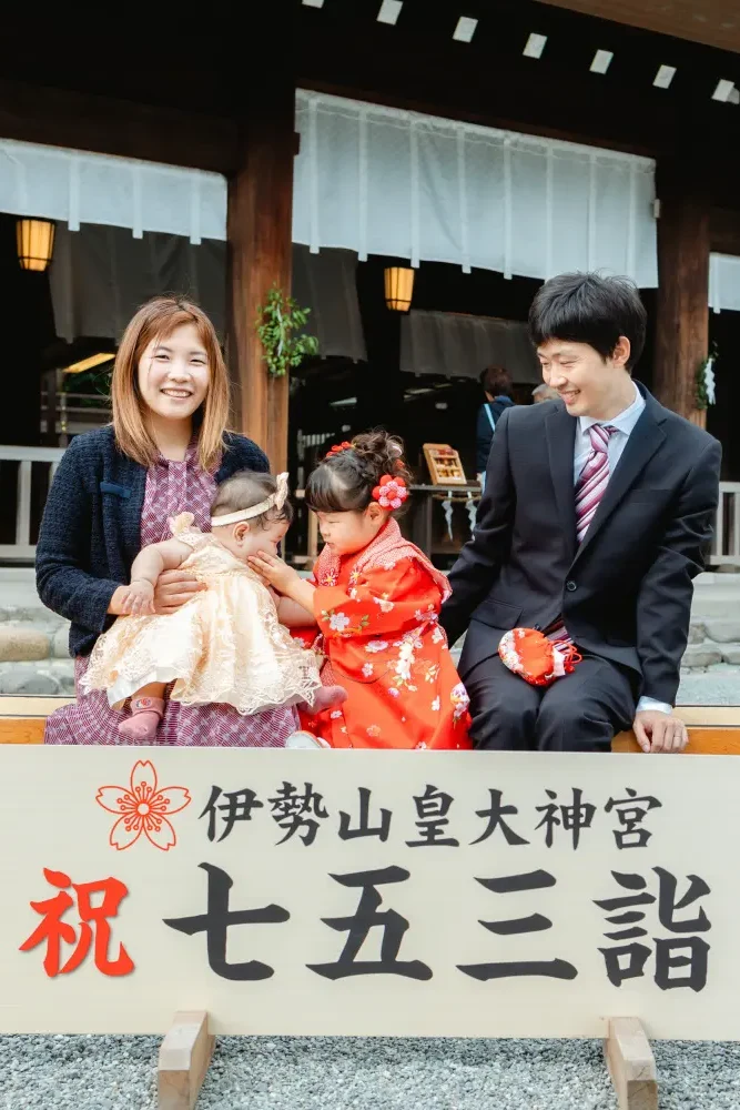 「祝 七五三詣」の看板前のベンチに座る家族4人（伊勢山皇大神宮・横浜の七五三撮影）