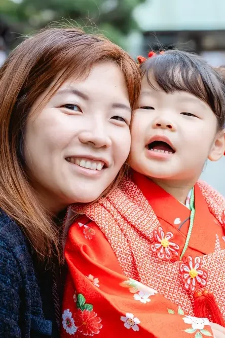 母と頬を寄せ合って笑う3歳の女の子、赤い被布姿の七五三（横浜）
