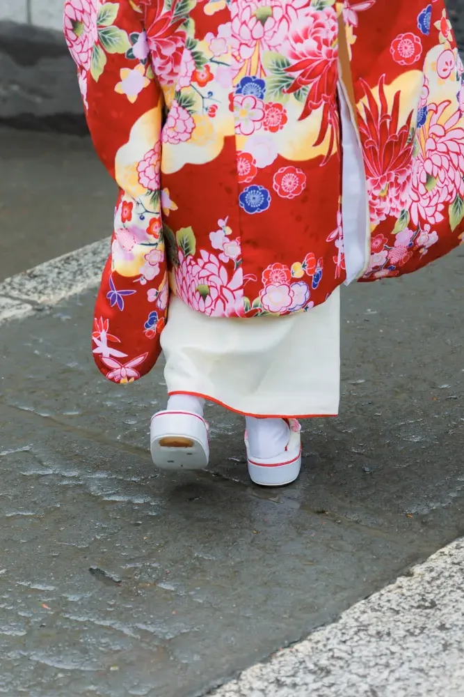 雨あがりで濡れた石畳を歩く3歳の女の子の足元、赤い被布と白い草履（伊勢山皇大神宮・横浜の七五三出張撮影）