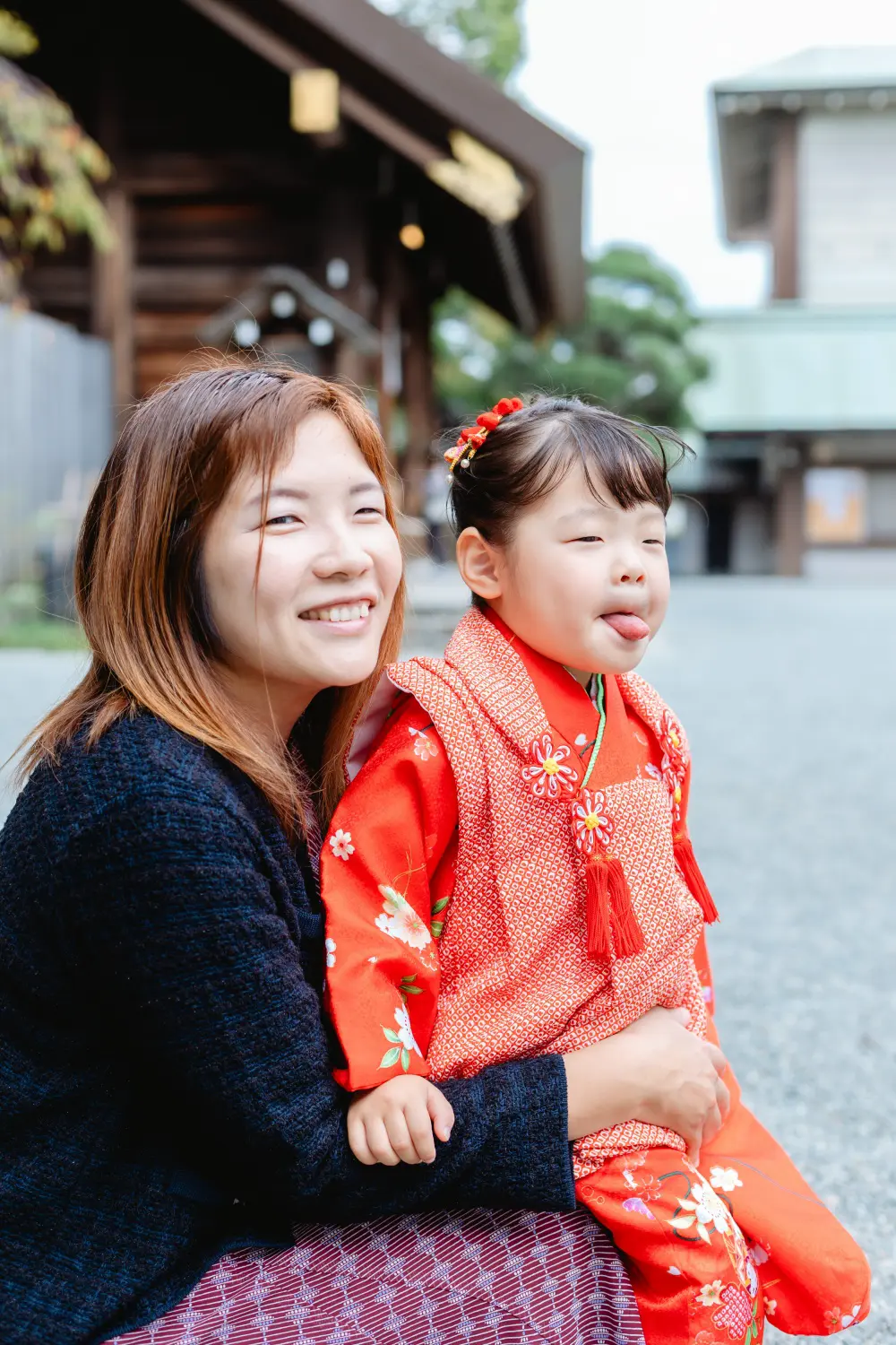 母の膝の上で舌を出しておどける3歳の女の子、七五三（伊勢山皇大神宮・横浜）