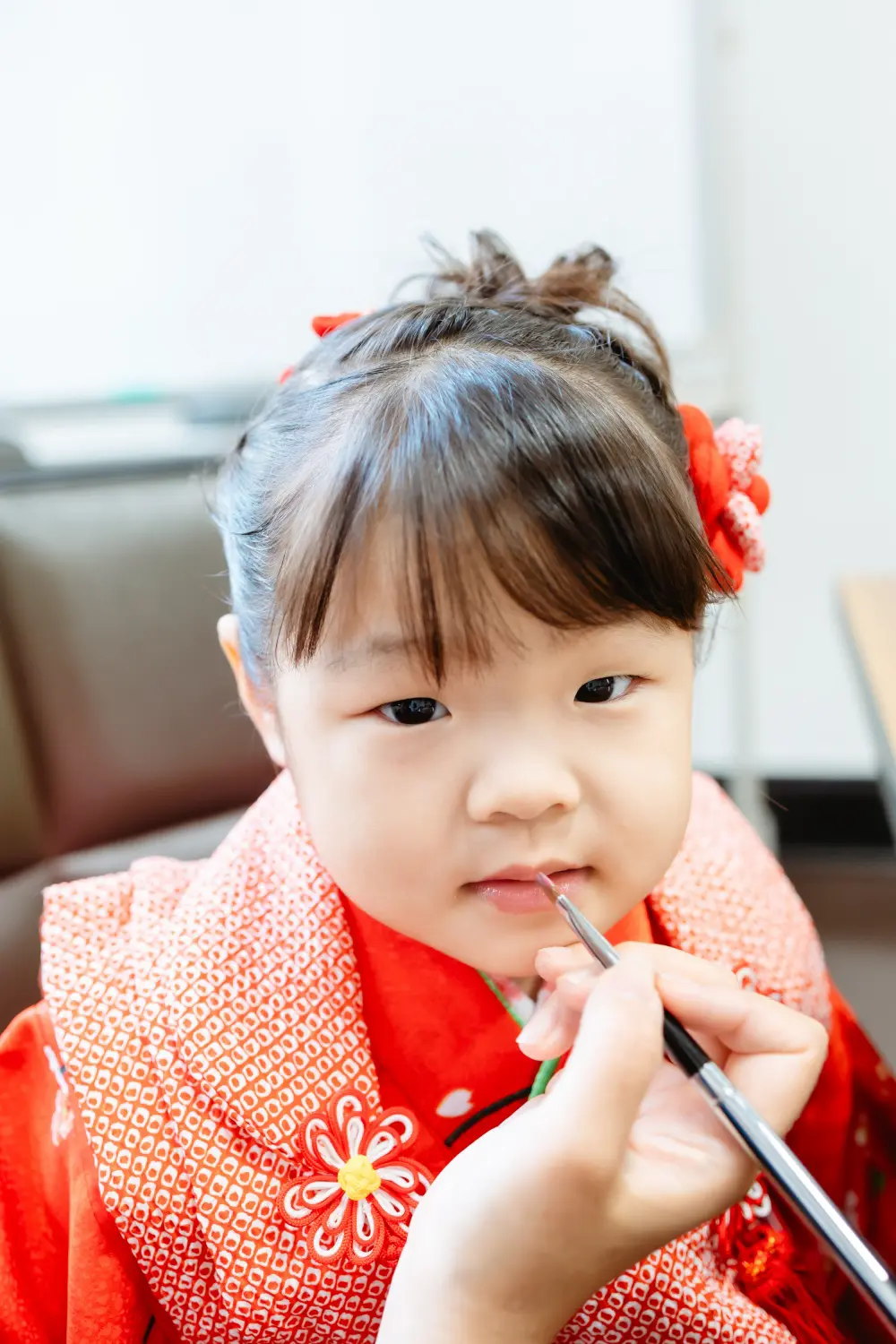 赤い絞りの被布姿で紅をさしてもらう3歳の女の子、七五三の支度（伊勢山皇大神宮・横浜）