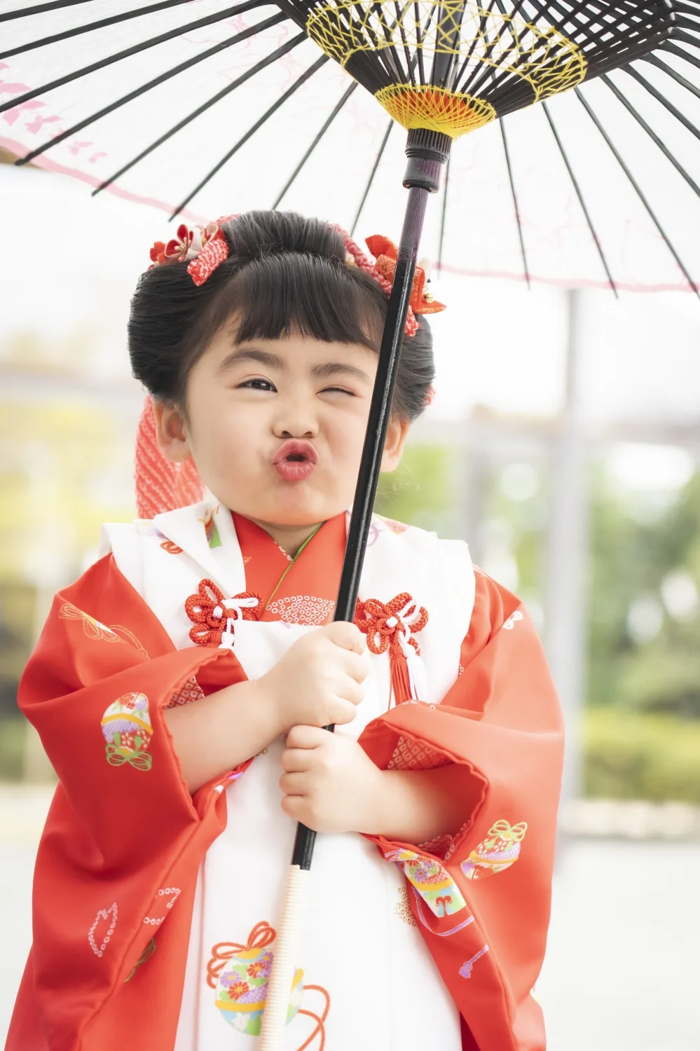 和傘を手に口をとがらせておどける3歳の女の子、被布姿（七五三・伊勢山皇大神宮）