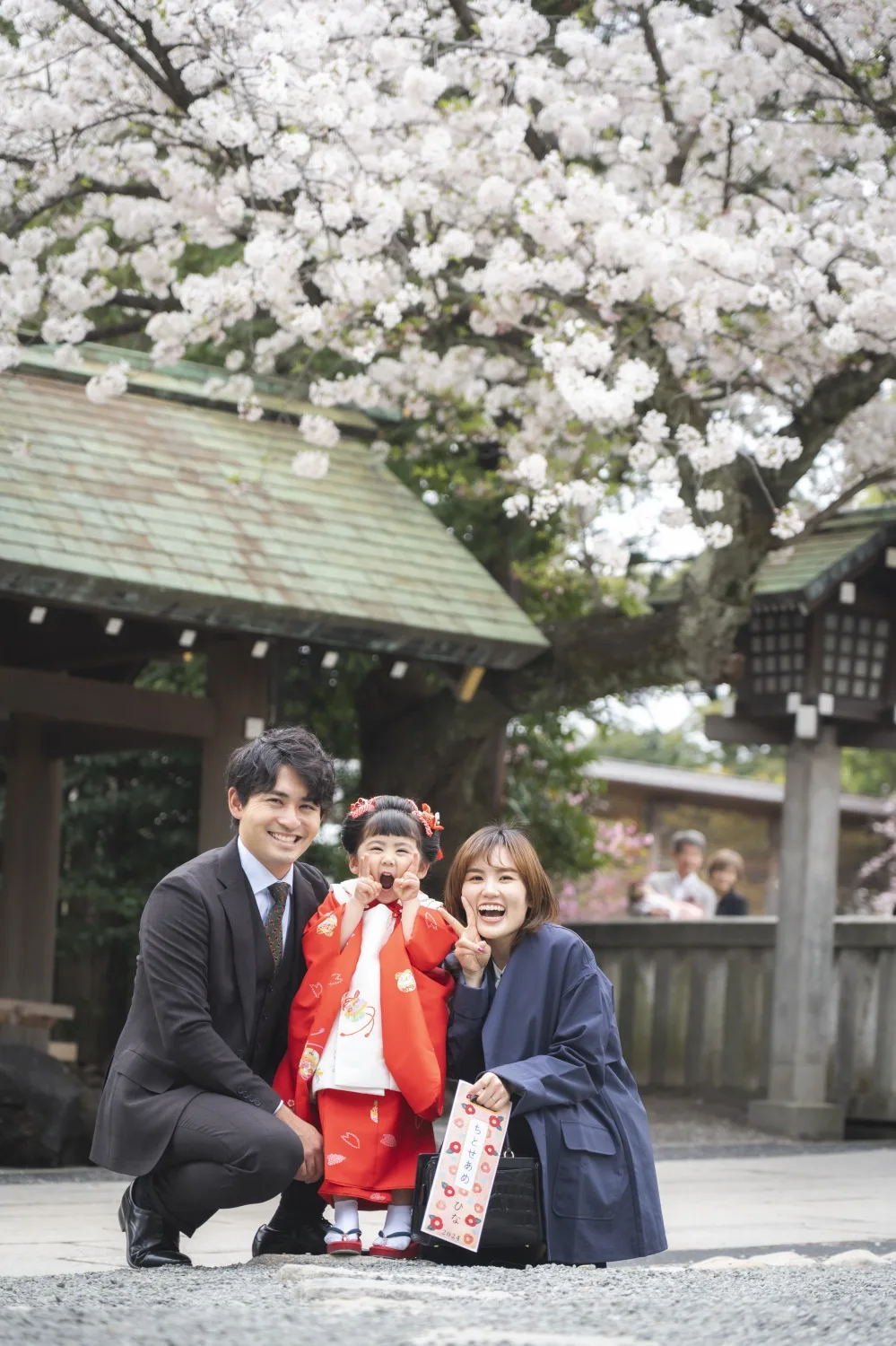 石鳥居と桜を背にしゃがんで並ぶ家族3人の七五三集合写真（横浜）
