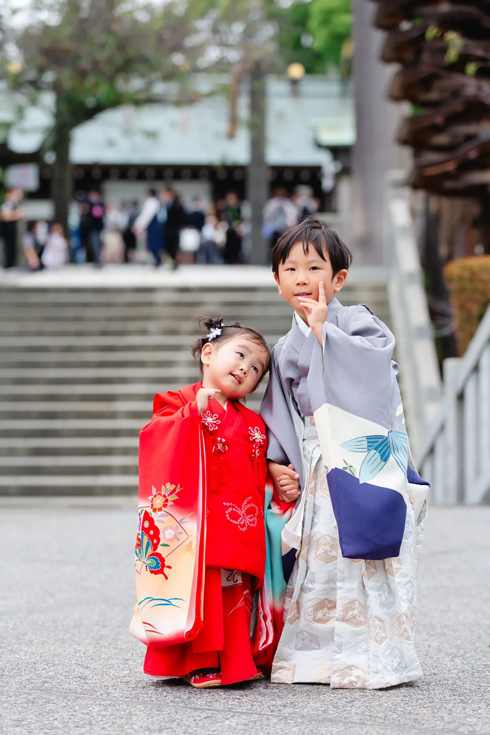 手をつなぎ頬に指をあててポーズをとる兄妹の七五三、被布と羽織袴（伊勢山皇大神宮・横浜）