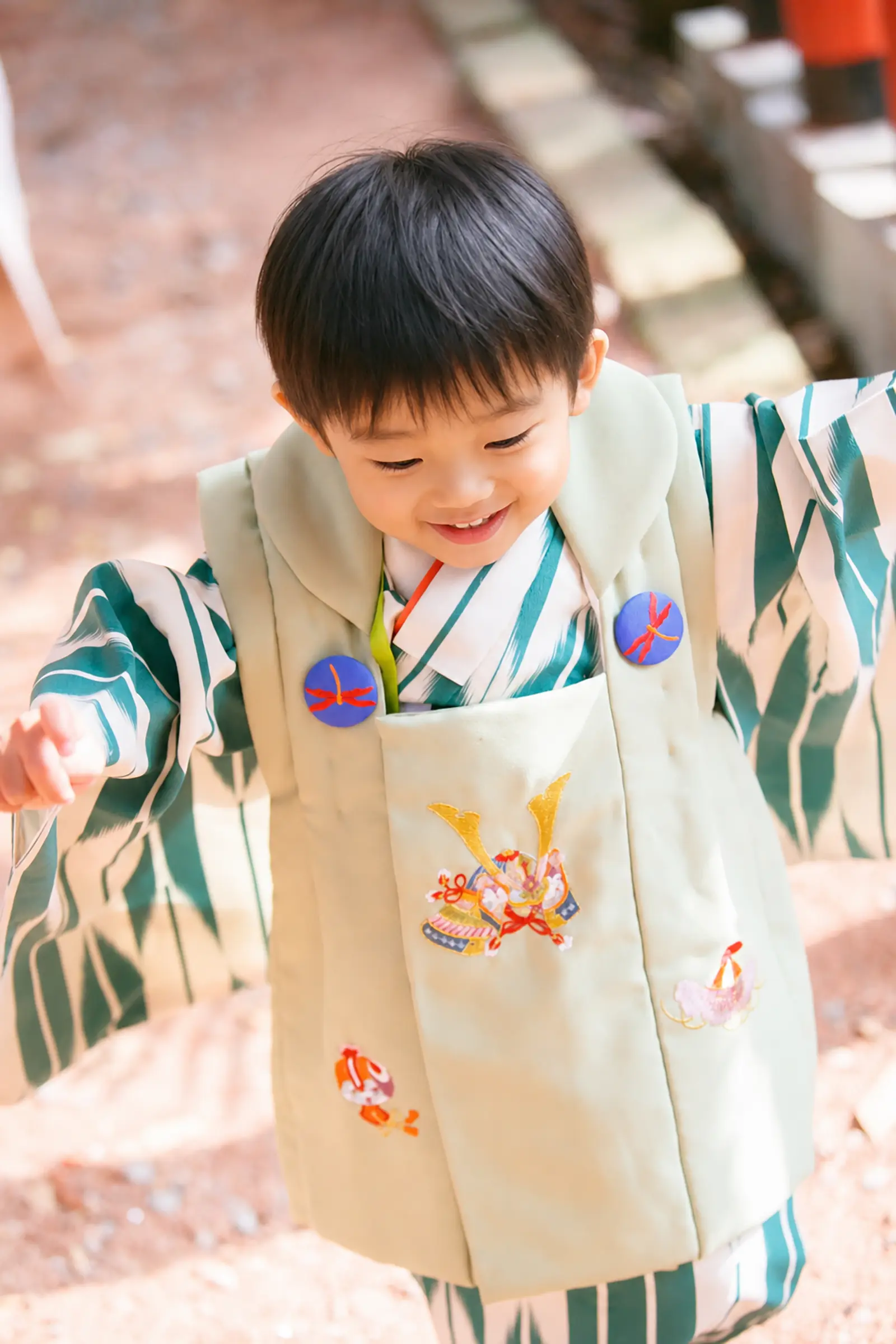 真上から見下ろした若草色の被布コート、兜と毬の刺繍・赤とんぼの飾りボタン｜3歳男の子の七五三（石浦神社・金沢）