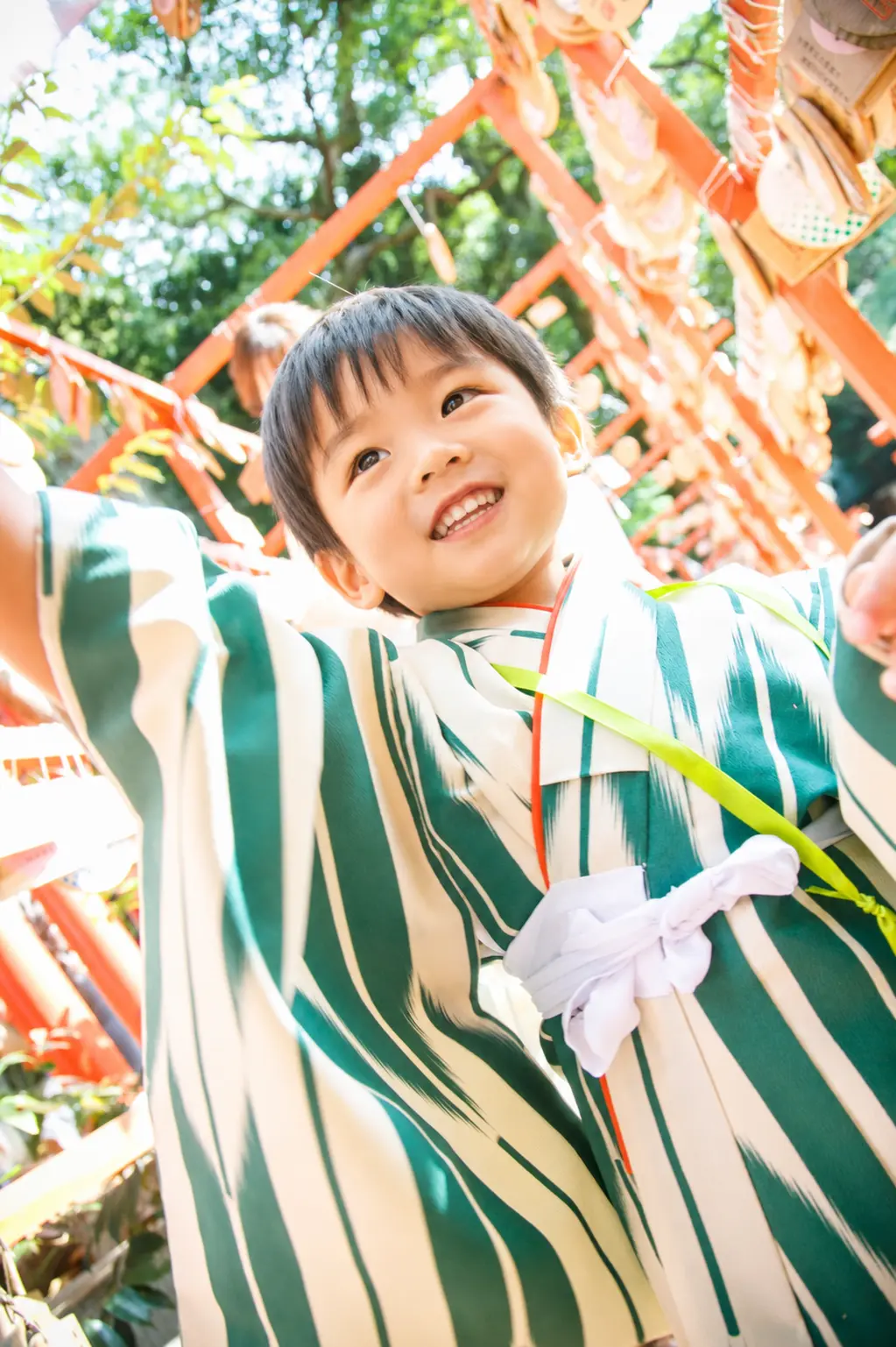 絵馬の下で両手を広げて笑う3歳の男の子、深緑と生成りの着物｜石浦神社の七五三出張撮影（金沢）