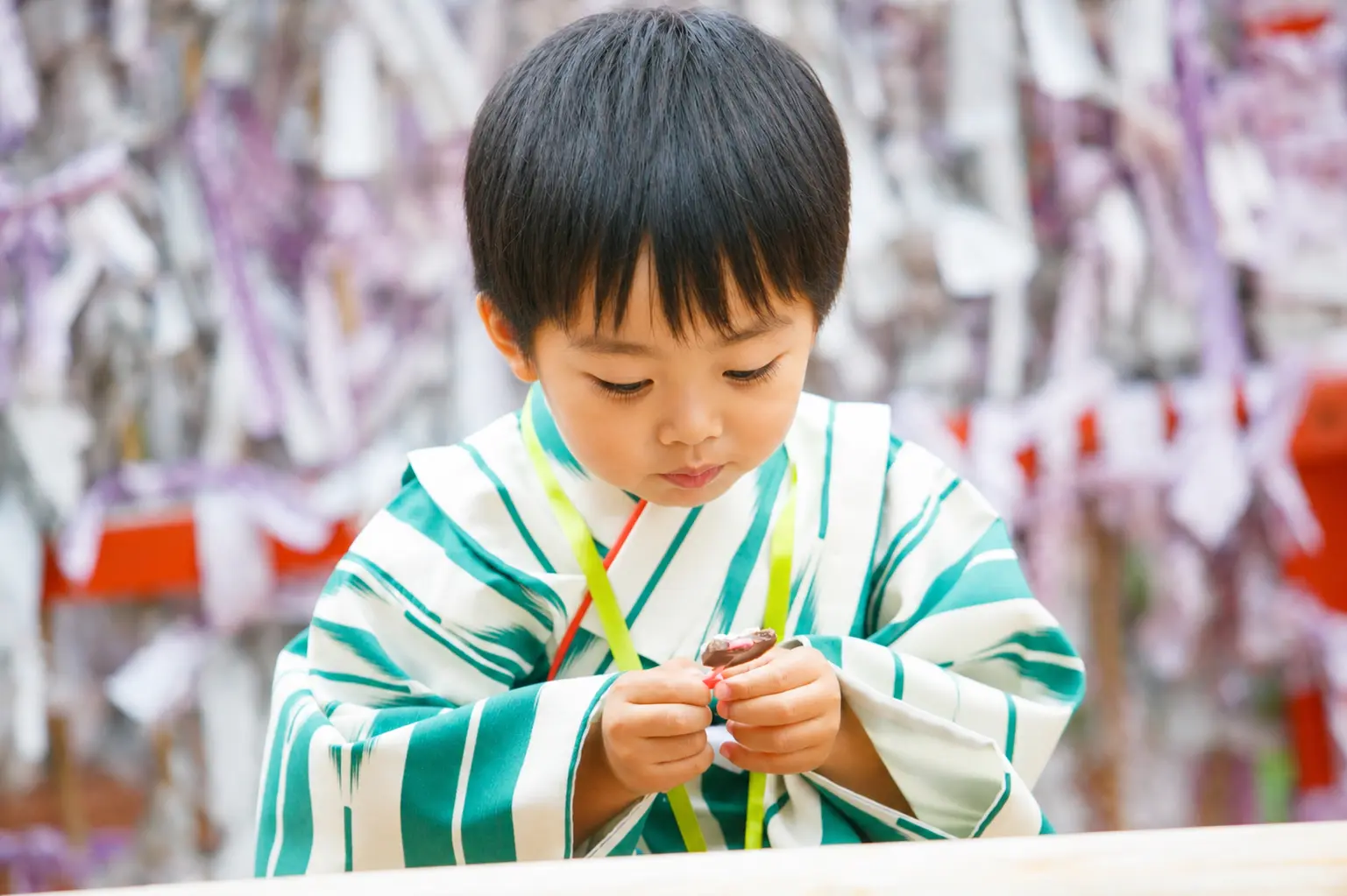 手のひらの小さなものをのぞきこむ3歳の男の子、深緑と生成りの着物｜石浦神社の七五三出張撮影（金沢）