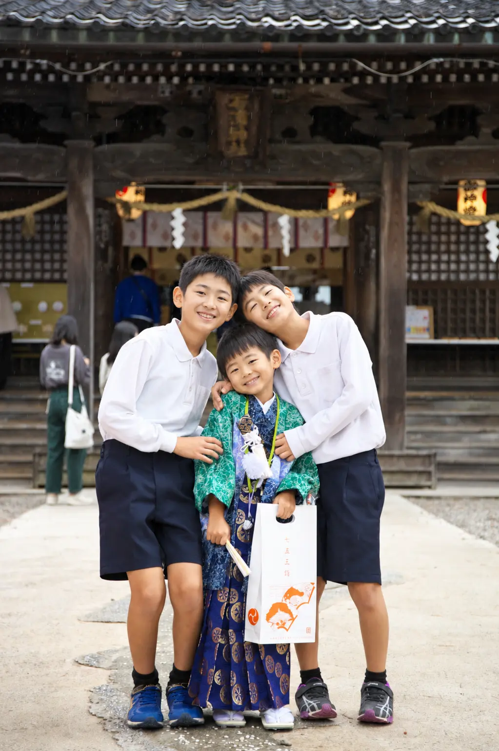 石浦神社の社殿前で肩を寄せ合う3人の兄弟、中央は5歳の羽織袴姿の七五三