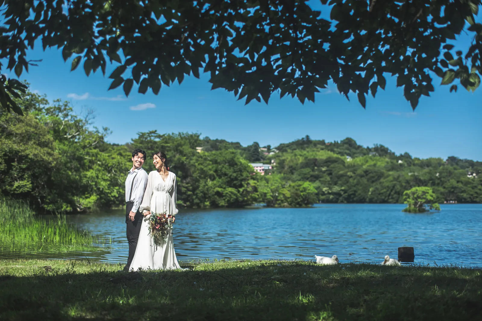 碧く澄んだ一碧湖の湖畔に並んで立つウェディングドレスの花嫁と新郎
