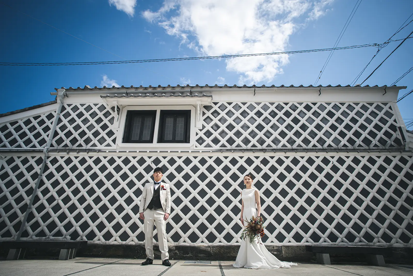 伊豆下田の伝統的ななまこ壁を背景に、白無垢と紋付袴姿で寄り添うカップル。フォトジェリッシュによる、歴史情緒あふれる洗練されたフォトウェディング。